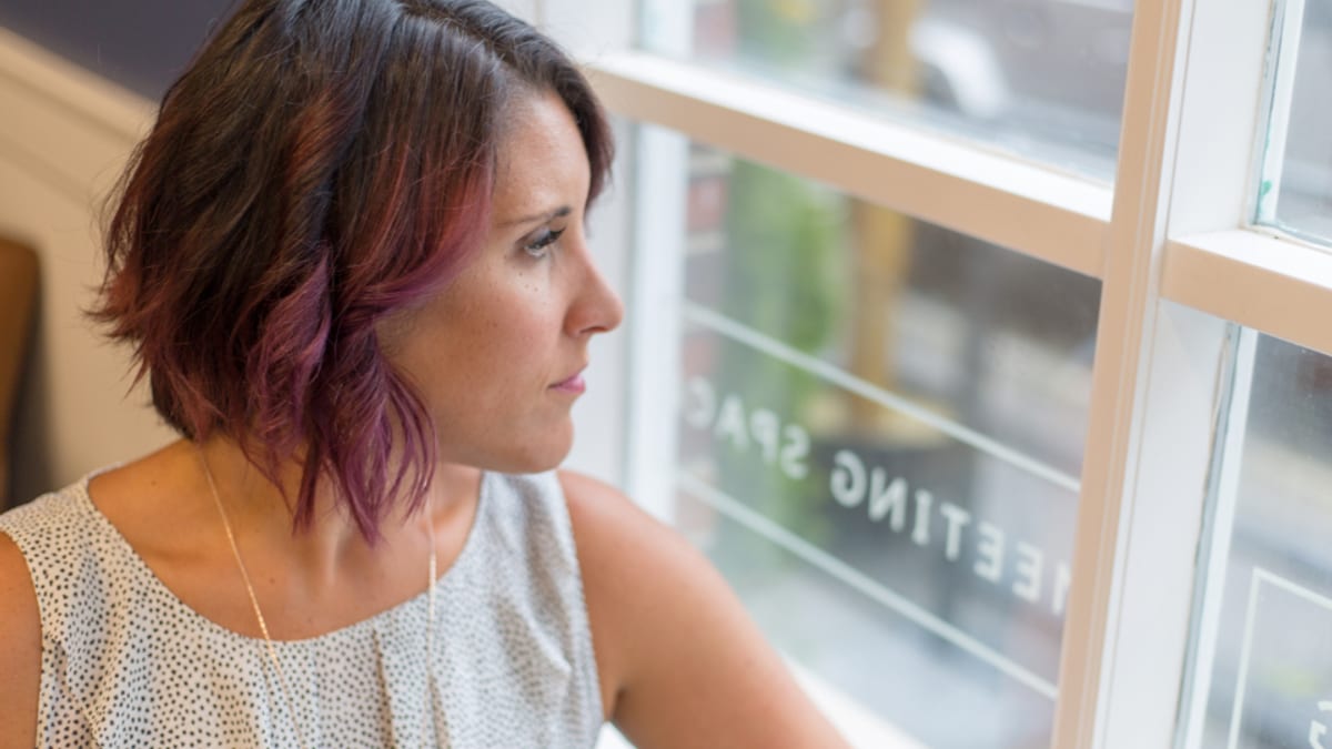A woman looks thoughtfully out of a window